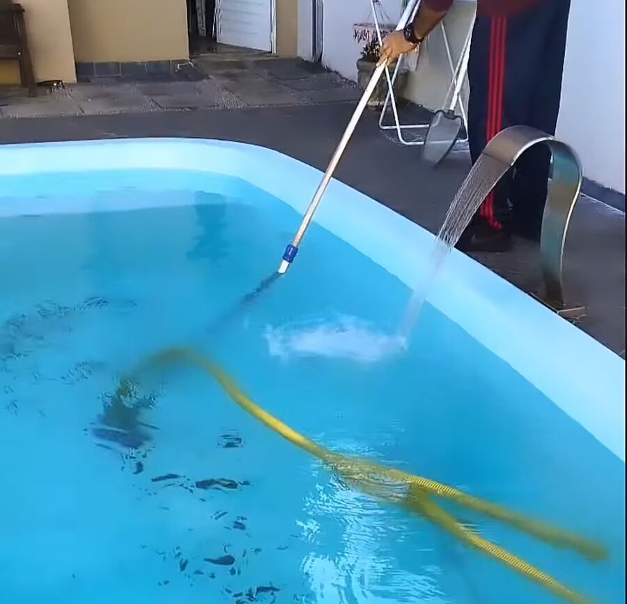 Luis aspirando uma piscina de fibra com água cristalina